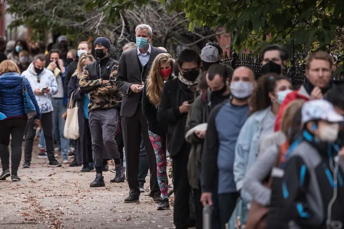 Mayor Bill de Blasio waits on a line with dozens of other people, all wearing masks, in Park Slope